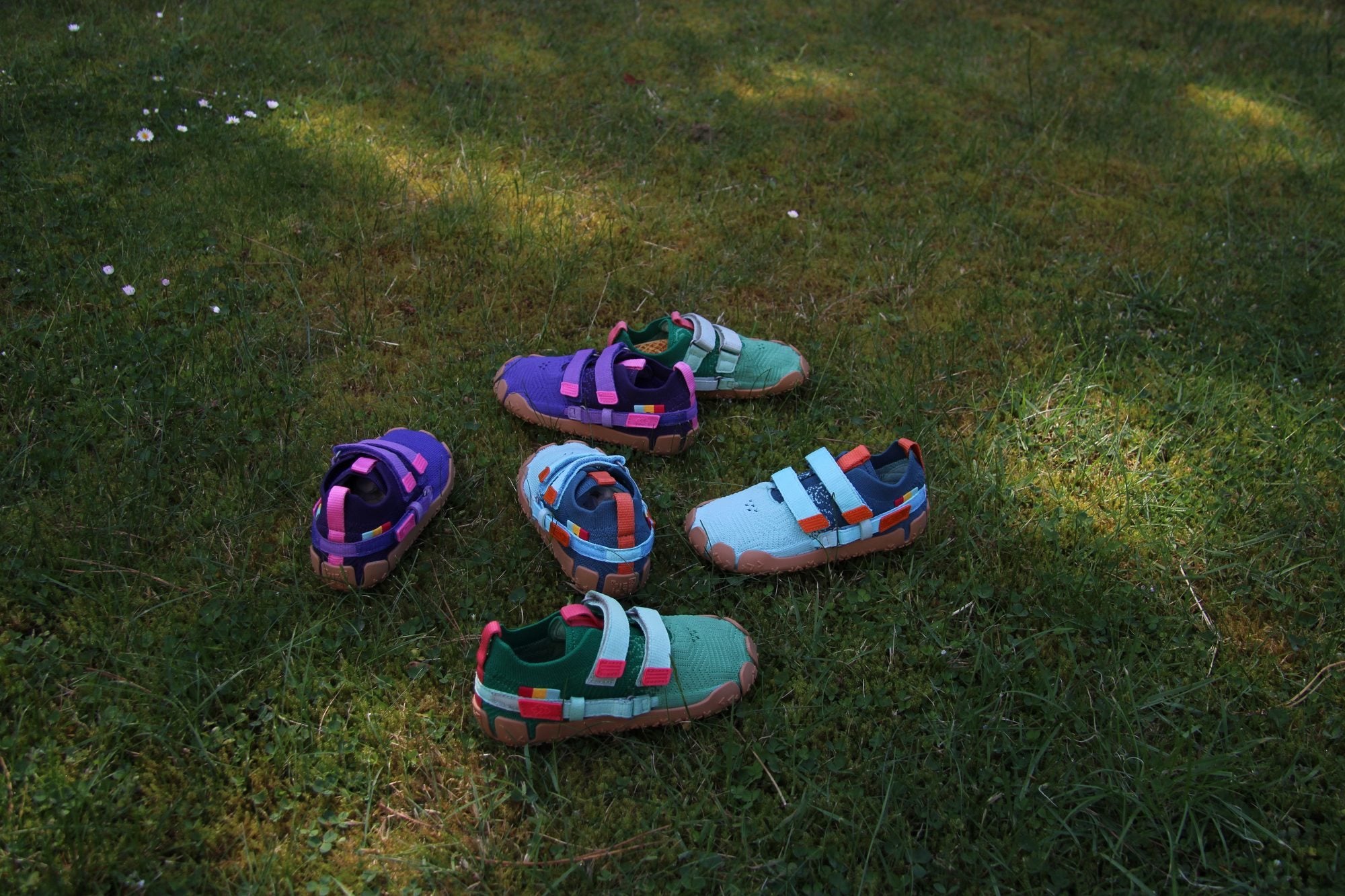 Sechs Sizeless Kinderschuhe in drei Farben im Gras
